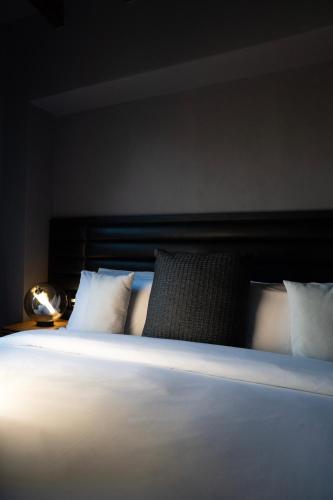 a bedroom with a bed with white sheets and pillows at Hotel Piedras Neg in San Miguel de Allende