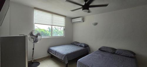 a room with two beds and a fan and a window at Mercado 28 Residences in Cancún
