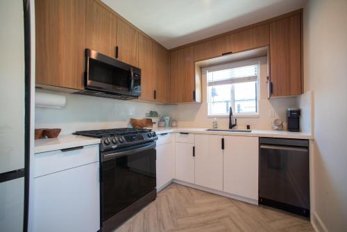 a kitchen with white cabinets and a black stove top oven at Modern 1 BR Cottage Steps 2Beach in San Diego