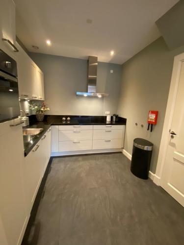 a large kitchen with white cabinets and a trash can at Van Doremaele Luxury Guesthouse in Velddriel