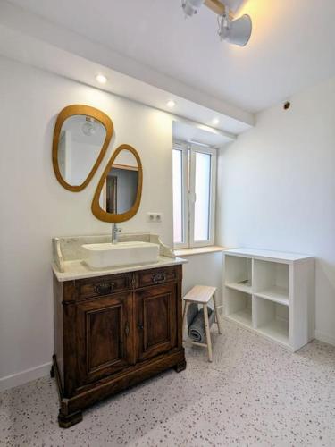 une salle de bain avec un lavabo et un miroir dans l'établissement Le grenier du Rempart, appartement au coeur du village, à Wattwiller
