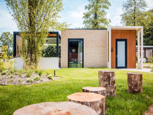 a house with tree stumps in the yard at Chalet in Veluwe with Peaceful Surroundings in Voorthuizen