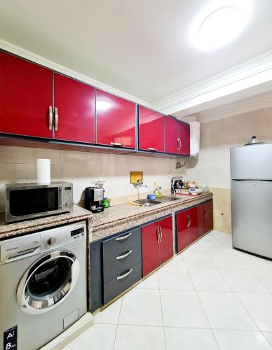 a kitchen with red cabinets and a white appliance at Luxury Apartment Fes - Family Suites in Fès