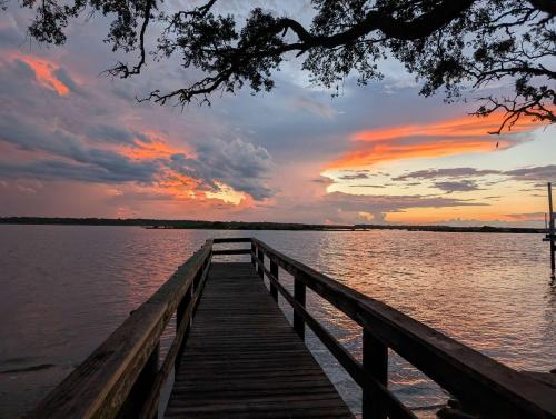 a wooden dock on a lake with a sunset at Coastal Condo - Walk to Beach Pool Pickleball and Boat Ramp in Saint Augustine