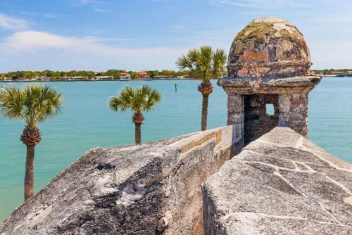 a rock with palm trees in front of the water at Coastal Condo - Walk to Beach Pool Pickleball and Boat Ramp in Saint Augustine