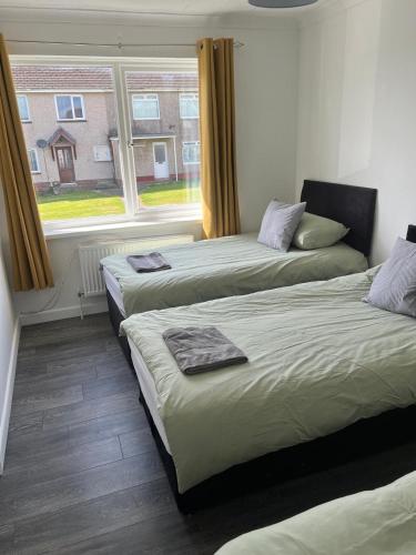 two beds in a room with a window at Sleeps 7 in Pembrokeshire