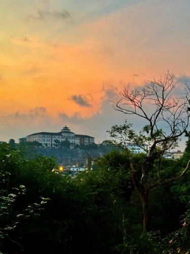a view of a building at sunset with a tree at Coorg Nature Breeze home stay in Madikeri