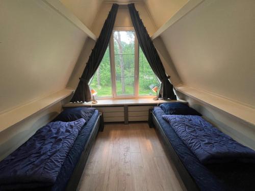 StramproyにあるSemi-detached bungalow 'Muizenoortje' at park Vossevenのベッド2台と窓が備わる屋根裏部屋です。