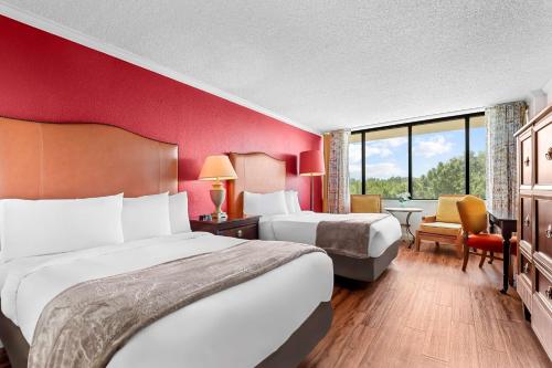 two beds in a hotel room with red walls at Magnolia Bluffs, BW Signature Collection in Natchez