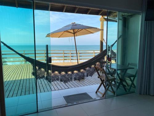 a hammock and an umbrella on a balcony with the beach at Hibisco Guest House in Florianópolis