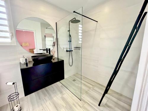 a bathroom with a glass shower and a sink at Villa PINK in Saint-François