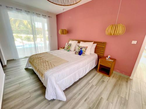 a bedroom with a large bed in a pink wall at Villa PINK in Saint-François