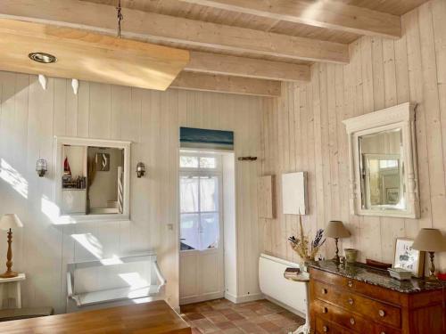 Cette chambre dispose de murs blancs, d'une fenêtre et d'une commode. dans l'établissement Maison de ville Chai Saint Martin de Ré, à Saint-Martin-de-Ré