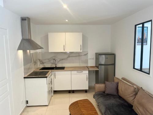 une cuisine avec des armoires blanches et un canapé dans une pièce dans l'établissement Gzenaya, à Avignon