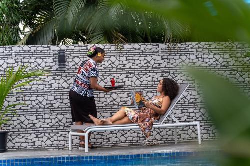a man and a woman sitting on a bench next to a pool at Airport Ace Hotel in Nadi