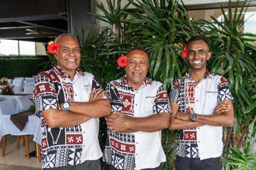 a group of three men standing with their arms crossed at Airport Ace Hotel in Nadi