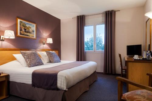 a hotel room with a bed and a window at The Originals City, Hôtel Paray-le-Monial in Paray-le-Monial