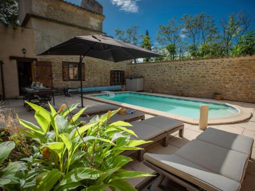 - une piscine avec un parasol, des chaises et une table dans l'établissement Le Pigeonnier de Villefloure, à Montréal