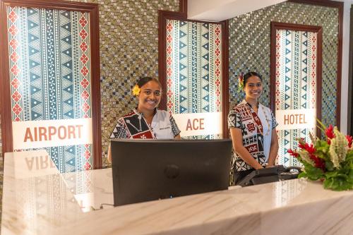a man and two women standing behind a desk with a laptop at Airport Ace Hotel in Nadi