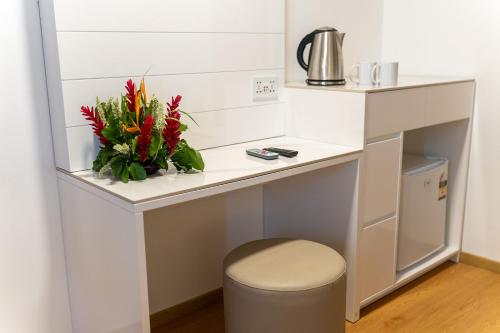 a white desk with a vase of flowers on it at Airport Ace Hotel in Nadi