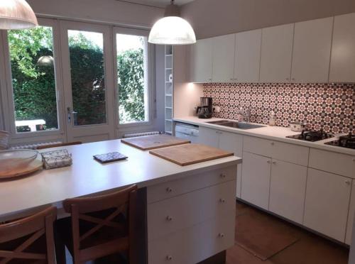 une cuisine avec des armoires blanches et une table avec des chaises dans l'établissement La Rose des Sables, Maison familiale 7 chambres, grand jardin, proche plage, à Houlgate
