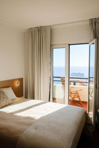 a bedroom with a large bed and a balcony at Funchal Sunset Apartment in Funchal