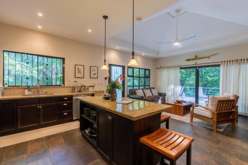 a kitchen with a large island and a living room at Four Winds Properties A Short Walk to the Beach in Nosara