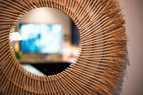 a wicker mirror reflecting a room with a television at Four Winds Properties A Short Walk to the Beach in Nosara