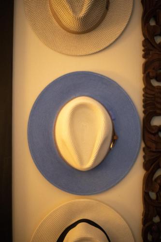 a blue hat on a wall with three hats at Four Winds Properties A Short Walk to the Beach in Nosara