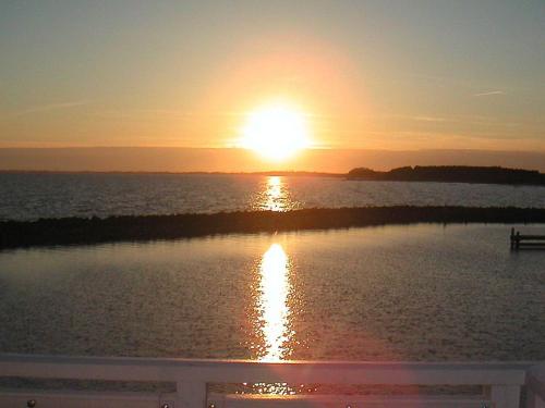 a sunset over a body of water with the sun setting at Apartment Borre VIII in Borre