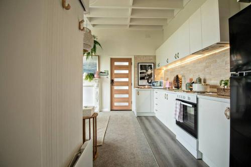 a kitchen with white cabinets and a stove top oven at Charming Hideaway Apartment Near St Kilda in Melbourne