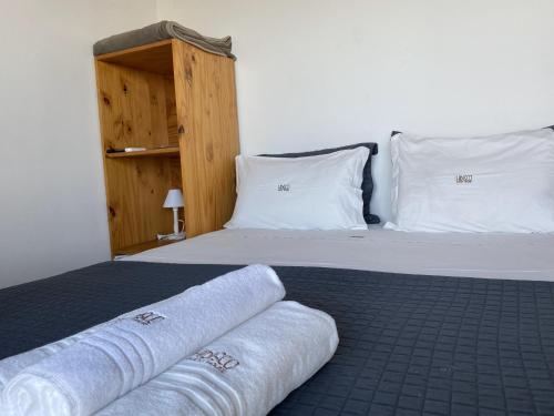 a bedroom with a bed with white pillows and towels at Hibisco Guest House in Florianópolis