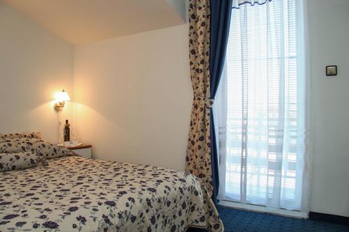 a bedroom with a bed and a large window at Hotel Villa Neretva - Metković in Metković