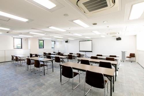 an empty classroom with tables and chairs and a whiteboard at Hotel Wing International Sagamihara in Sagamihara