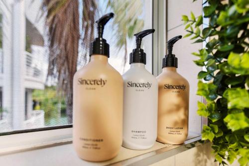 a group of three shampoo bottles sitting on a window sill at Melaleuca Hideaway - Beach Pool free parking in Yorkeys Knob