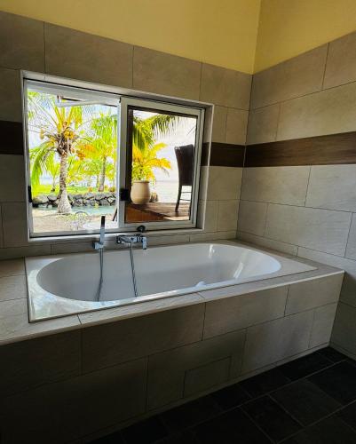 a bath tub in a bathroom with a window at La maison du Bonheur Raiatea in Tevaitoa