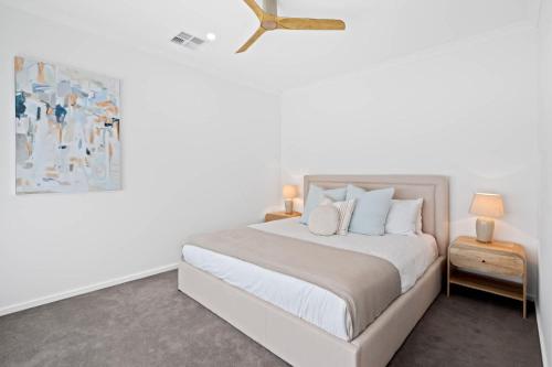 a white bedroom with a bed and a ceiling fan at Driftwood Port Noarlunga South in Port Noarlunga South