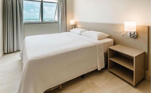 ein großes weißes Bett in einem Zimmer mit Fenster in der Unterkunft Flat em Resort Park Salinas vista a piscina in Salinópolis
