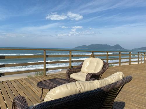 two chairs and a couch on a deck overlooking the ocean at Hibisco Guest House in Florianópolis