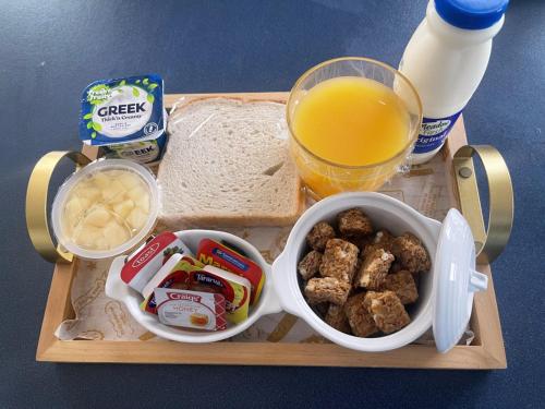 a tray of food with bread and a glass of orange juice at Bella Vista Motel Oamaru in Oamaru