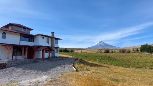 a house in a field with a mountain in the background at Cotopaxi Lodge in Hacienda Porvenir