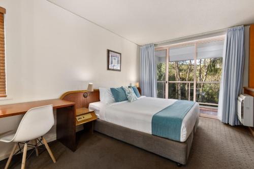 a hotel room with a bed and a desk and a window at Charlesworth Bay Beach Resort in Coffs Harbour