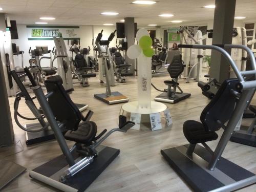 einen Fitnessraum mit Laufbändern und Crosstrainern in der Unterkunft Parkhotel Papenburg in Papenburg