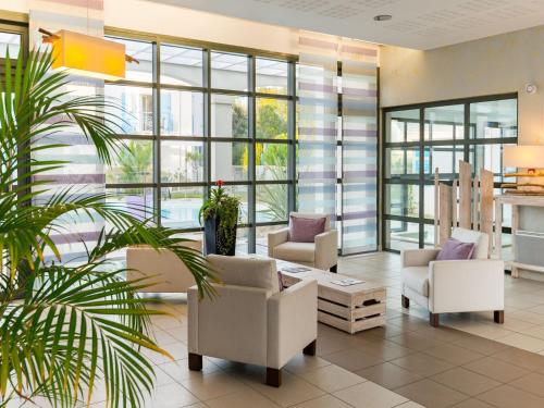 un hall avec des chaises blanches et un palmier dans l'établissement Apartment in France near the Coastline, à Saint-Palais-sur-Mer