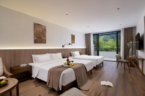 a hotel room with two beds and a table at Hilltop House Resort in Zhangjiajie