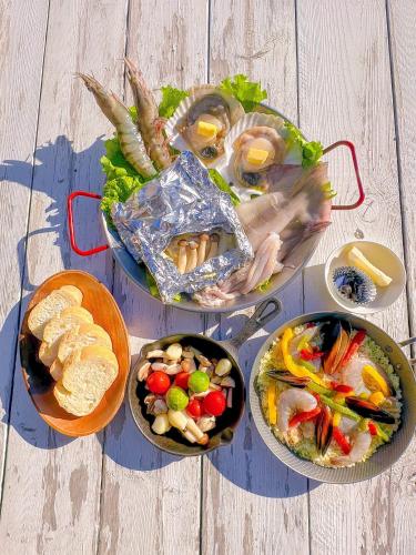 a table topped with plates of food with seafood and vegetables at Retreat Camp Mahoroba in Fujikawaguchiko