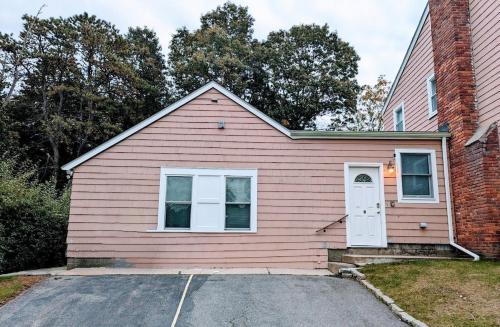 a pink house with a white door on a street at Spacious Two Bedroom Apartment in Wayland