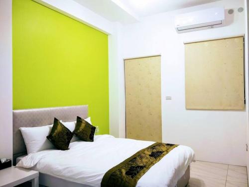 a bedroom with a bed with a green wall at 馬卡上將民宿 歡唱l麻將l烤肉BBQ in Sanxing