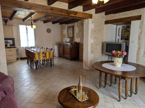 - un salon avec deux tables et une télévision dans l'établissement Gîte rénové 19ème siècle, 3 chambres, jardin privé, cheminée, internet, jeux, vélos adultes, parking - FR-1-653-26, à Louzignac