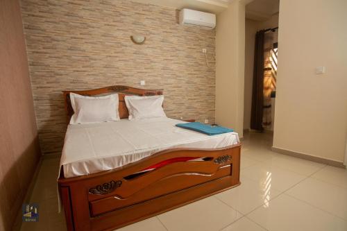 a bed in a room with a brick wall at Repavi Lodge in Yaoundé